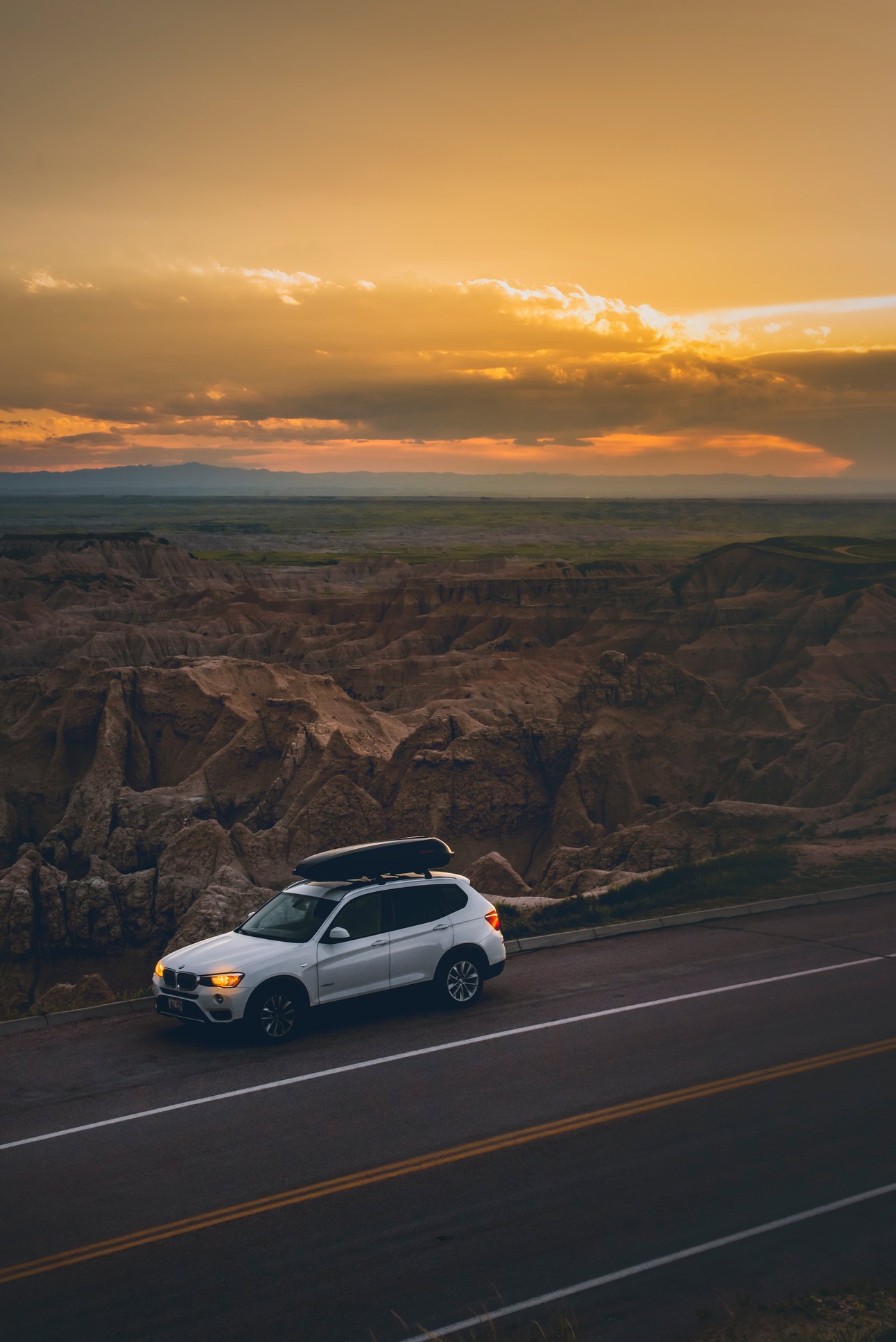 Car on side of road near mountain terrain during sundown